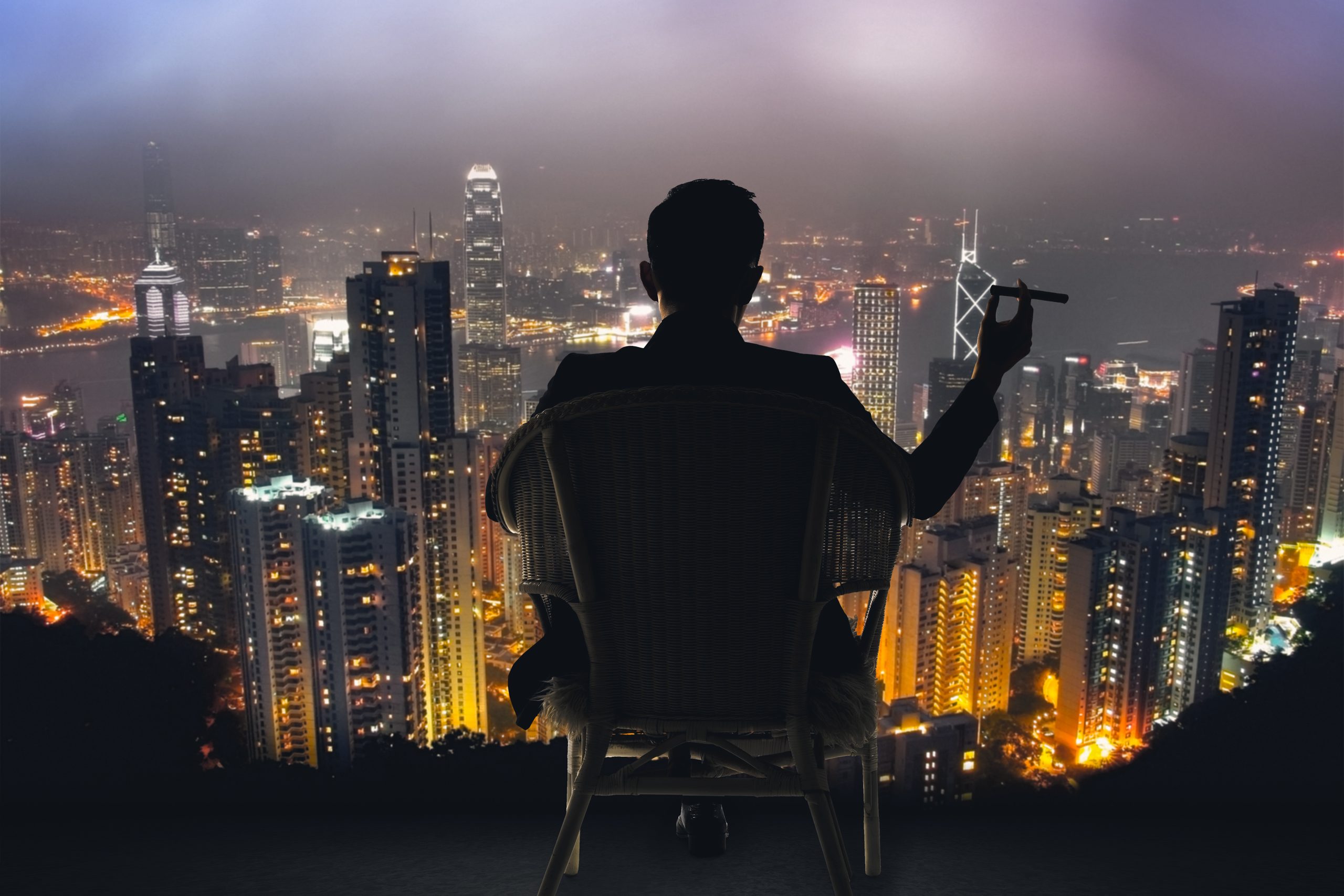 Silhouette of man sitting on a chair holding a cigar, overlooking a new york city skyline at night. hustler war manifesto